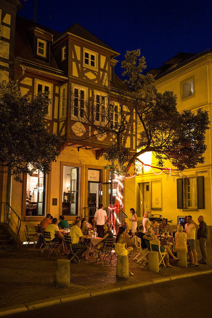 People outside bar 30 Leut' at night, Aschaffenburg, Franconia, Bavaria, Germany