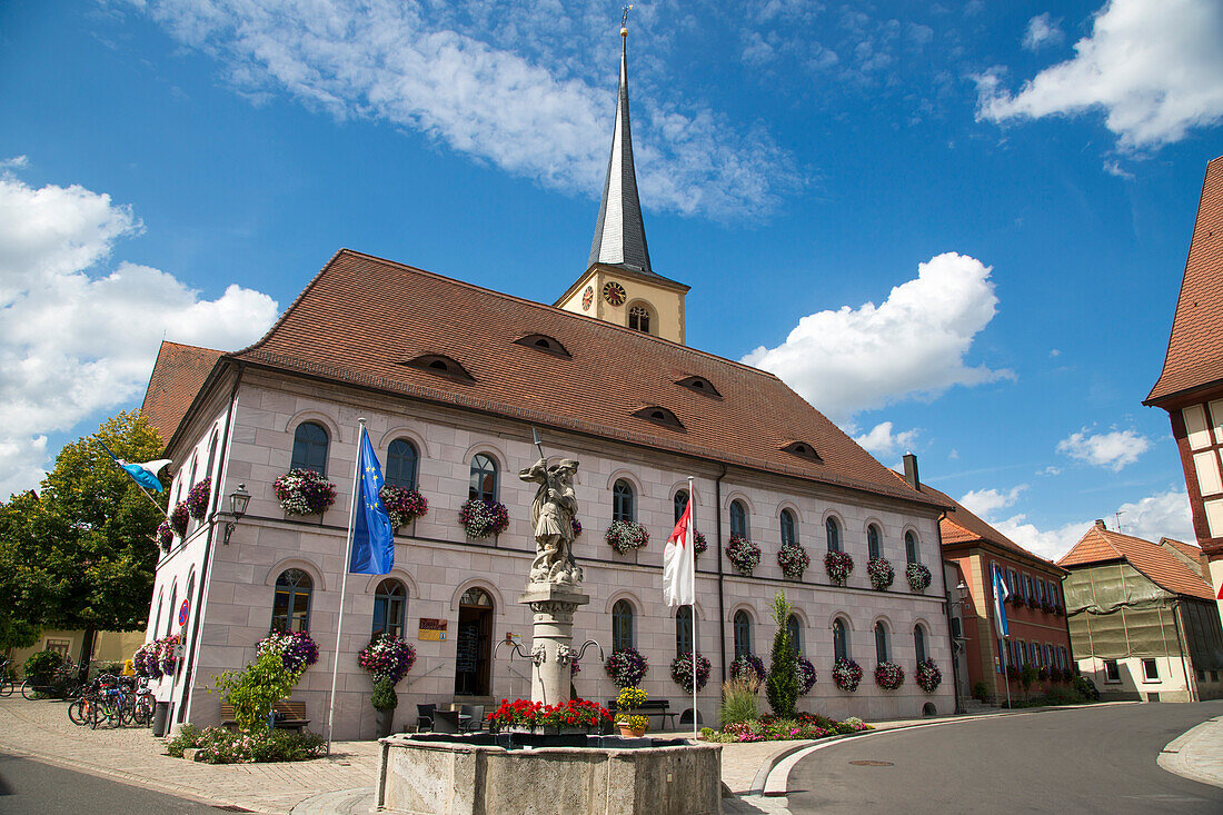 Fountain in front of Vinethek building with church tower behind, Sommerach, Franconia, Bavaria, Germany