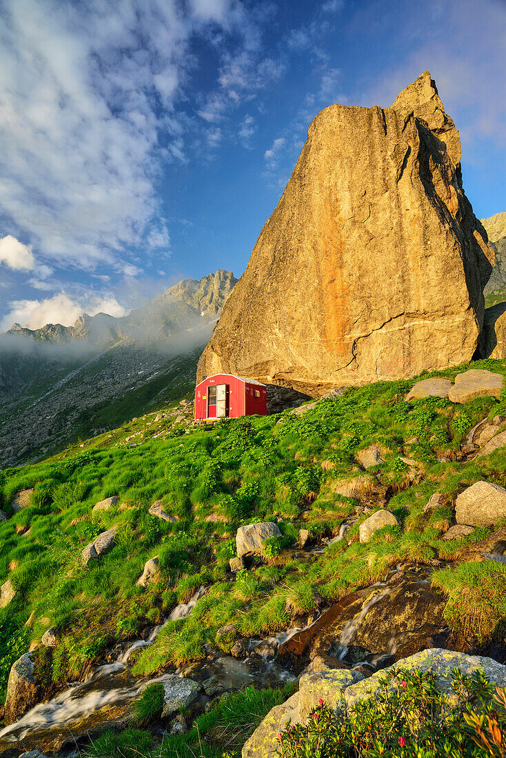 Red bivouac beneath boulder, Lombardy, Italy