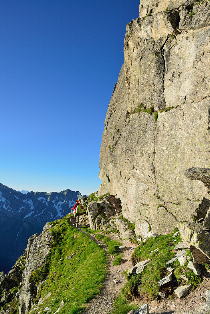 Frau beim Wandern unter Felswand, Sentiero Roma, Bergell, Lombardei, Italien