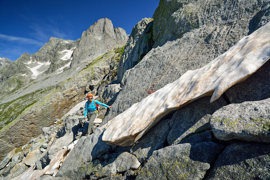 Woman hiking over rock slabs, Sentiero Roma, Bergell range, Lombardy, Italy
