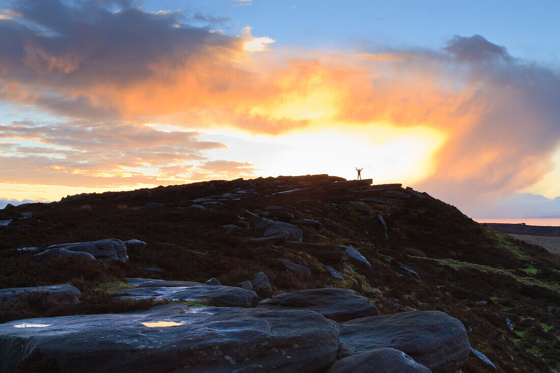 Person on rocks of Stanage Edge with winter sunrise, near Hathersage, Peak District National Park, Derbyshire, England, United Kingdom, Europe