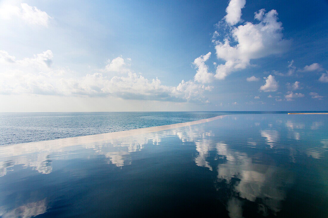 Infinity pool reflecting the sky and clouds with sea visible in the distance, Silavadee Pool Spa Resort, Koh Samui, Thailand, Southeast Asia, Asia