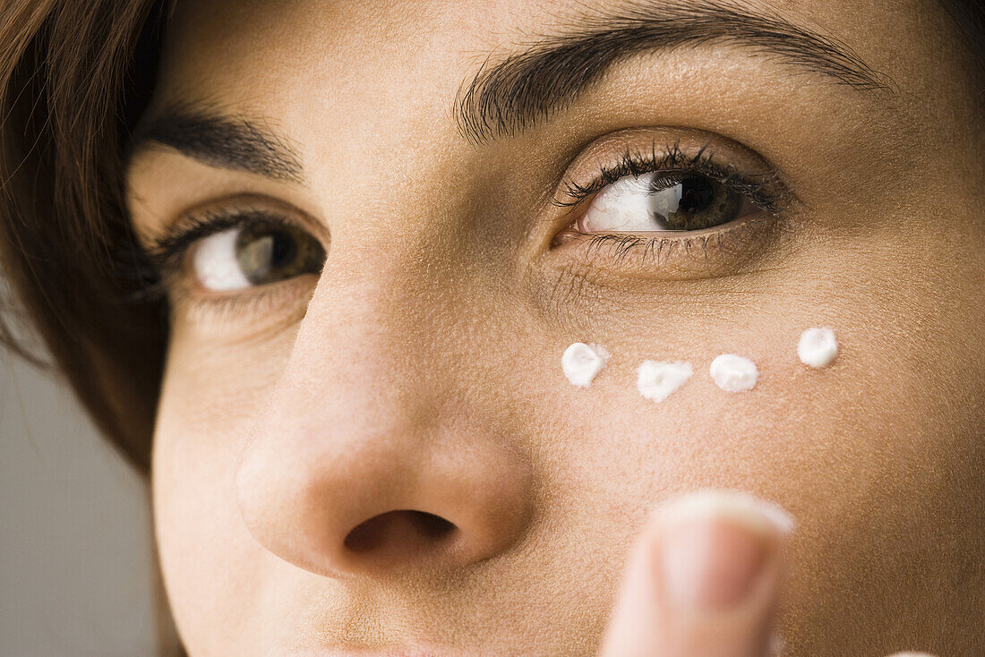 Young woman applying undereye cream