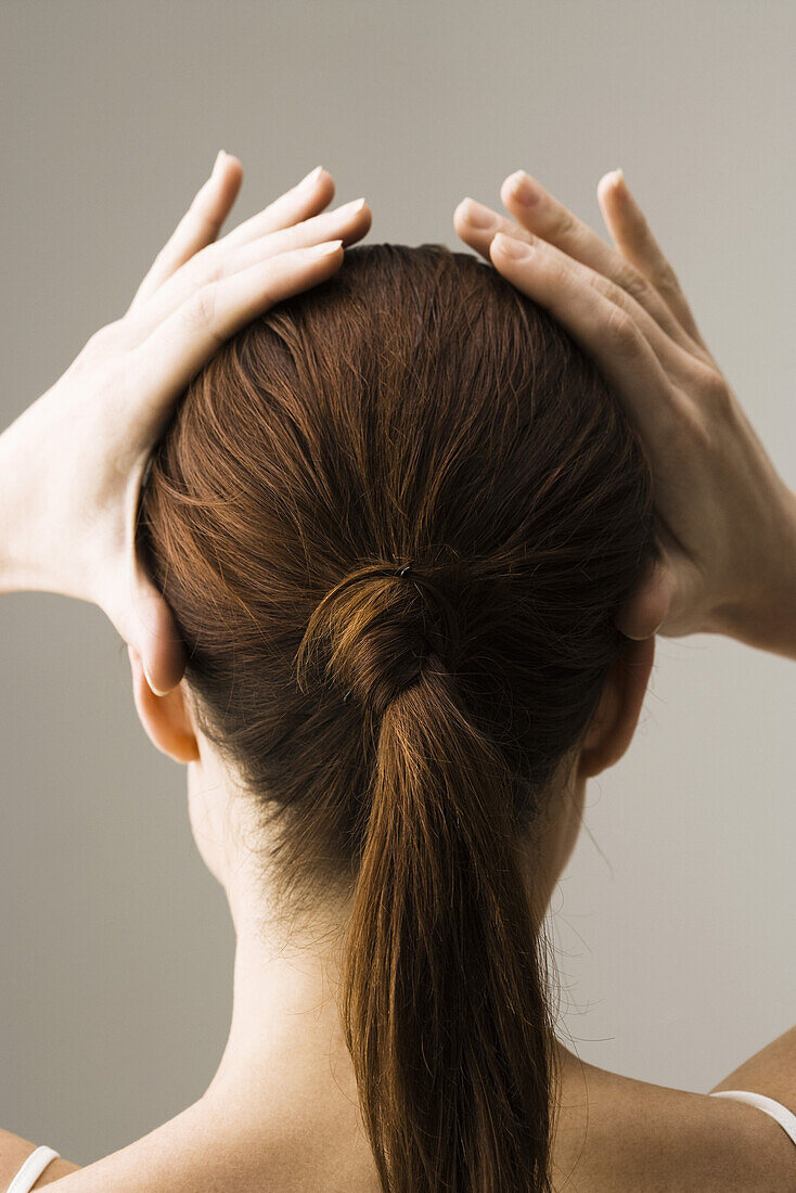 Frau beim Frisieren der Haare, Rückansicht