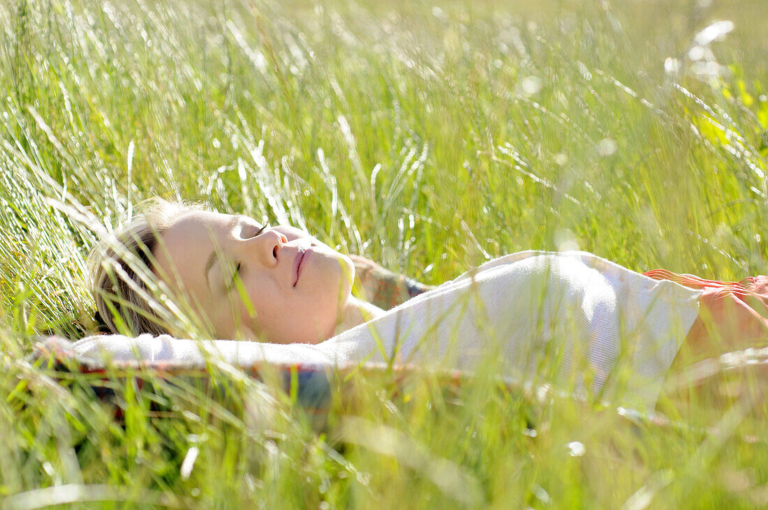 Young woman napping in tall grass