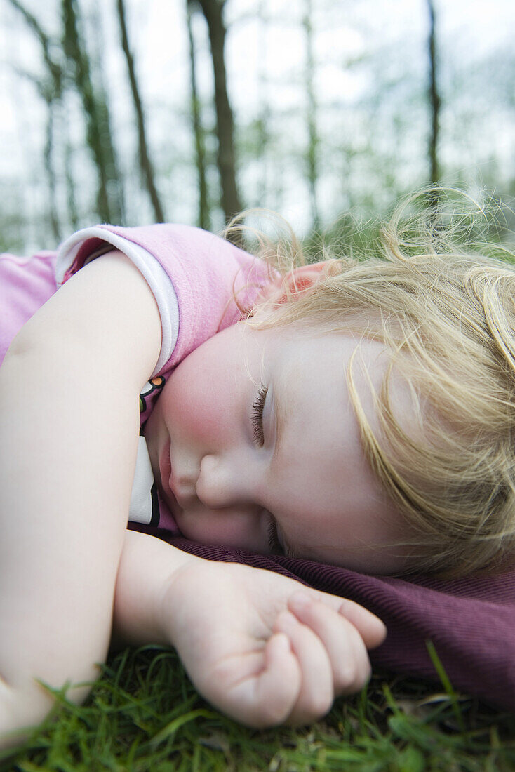 Toddler girl taking a nap outdoors