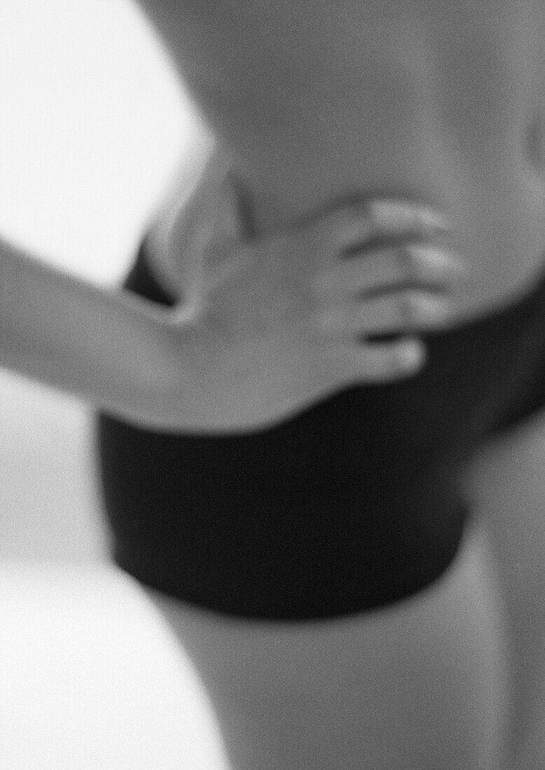 Woman with hand on hip, mid-section, blurred, close-up, B&W.