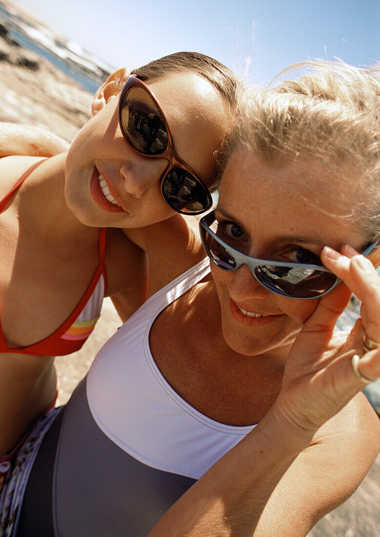 Close-up of woman and teenage girl wearing sunglasses at the beach.
