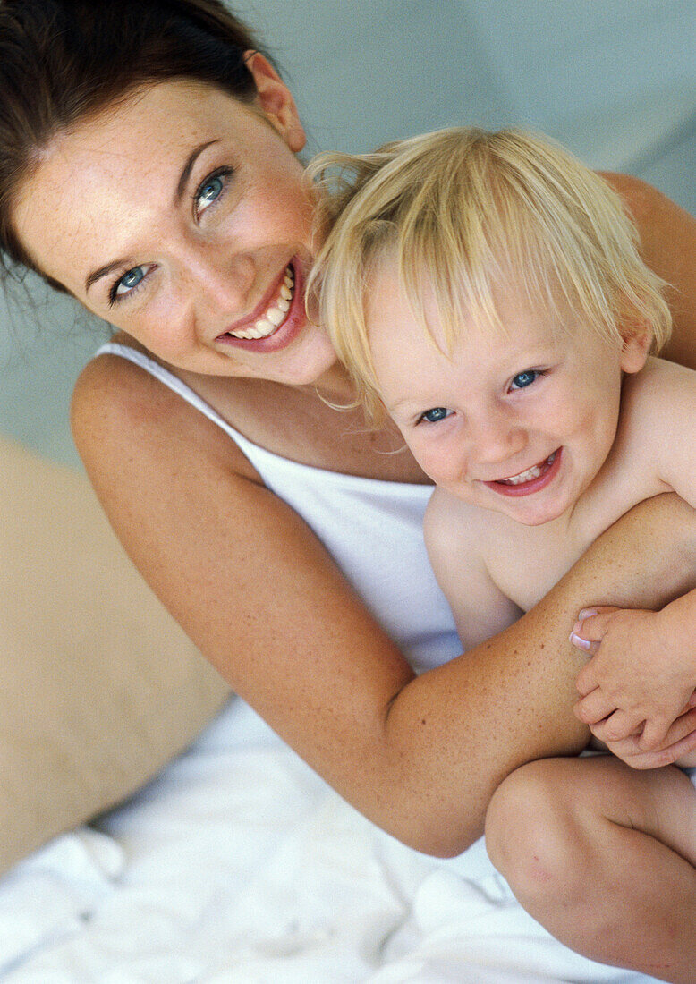 Mother hugging baby, smiling at camera