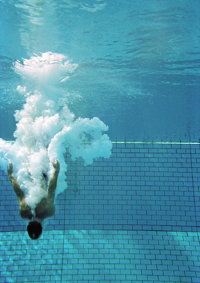 Person diving in water, underwater view.