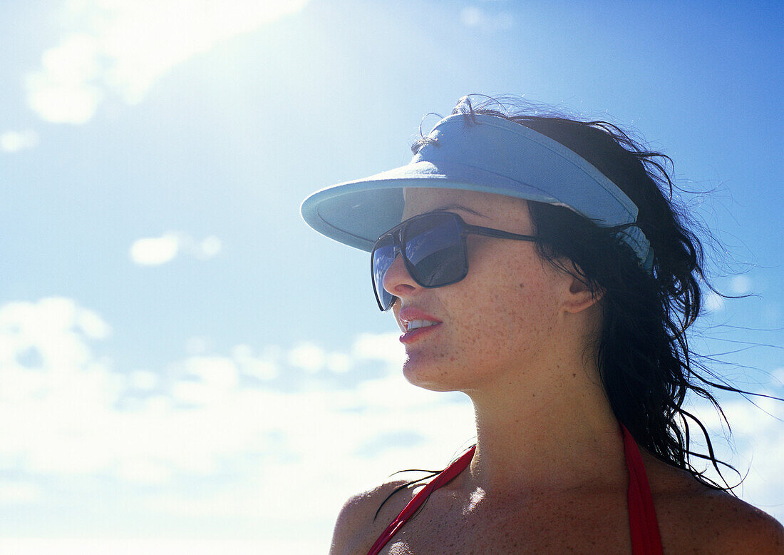 Woman wearing sunglasses and sun visor outdoors, portrait