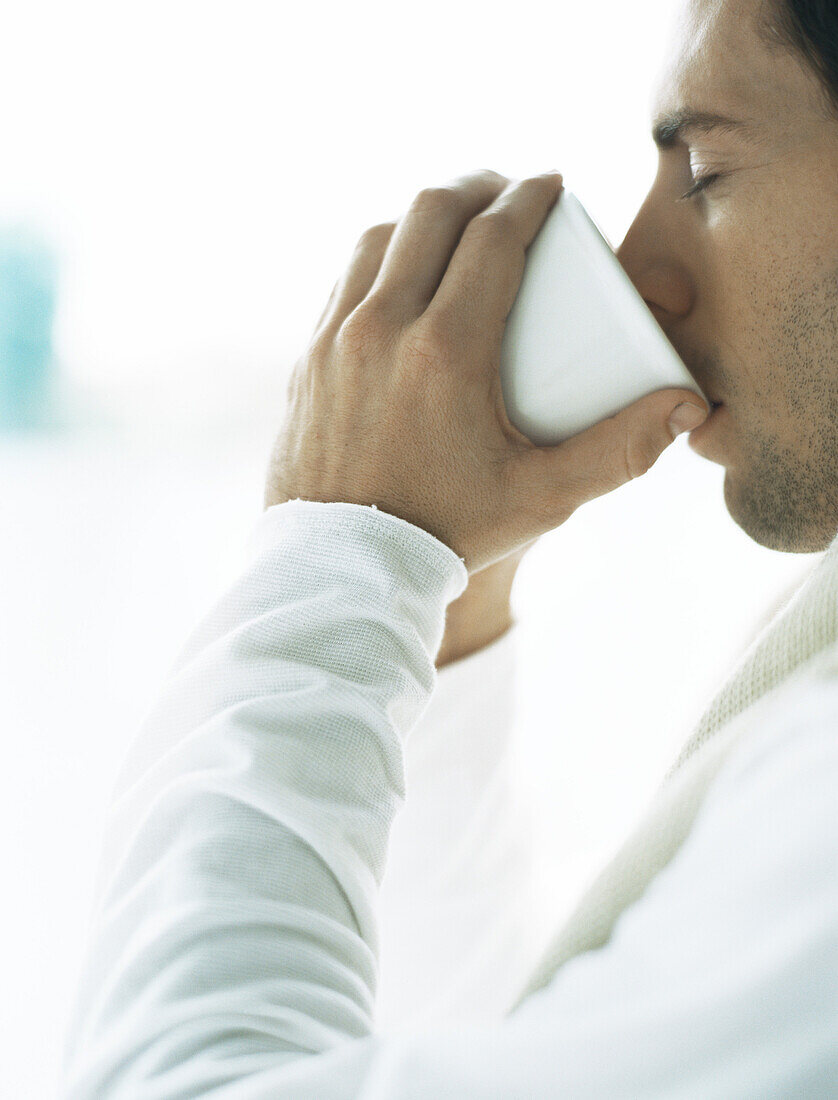 Man drinking from cup, eyes closed