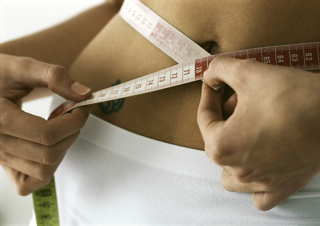 Woman measuring waist, close-up