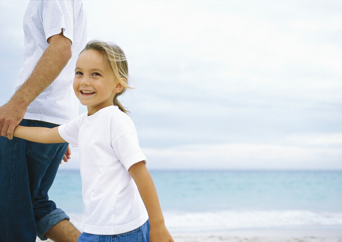 Girl walking with father on beach