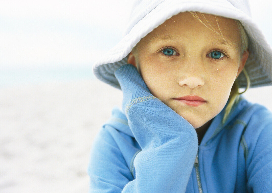 Little girl wearing hat on beach, portrait