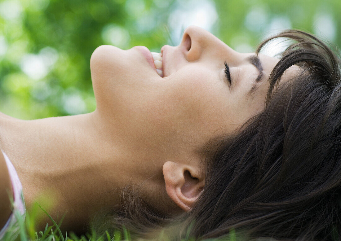 Young woman lying in grass with eyes closed