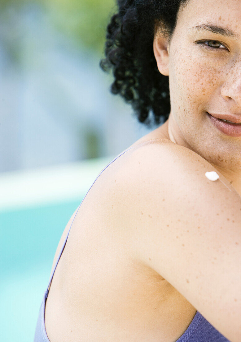 Junge Frau mit einem Tupfer Sonnencreme auf der Schulter