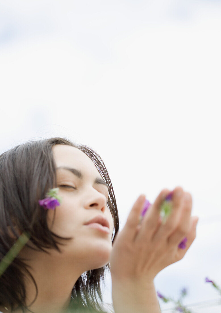 Young woman blowing flowers from hand