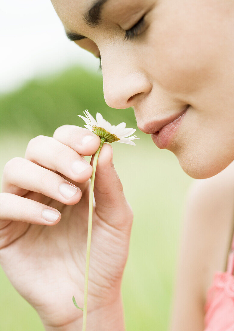 Junge Frau riecht an einer Blume