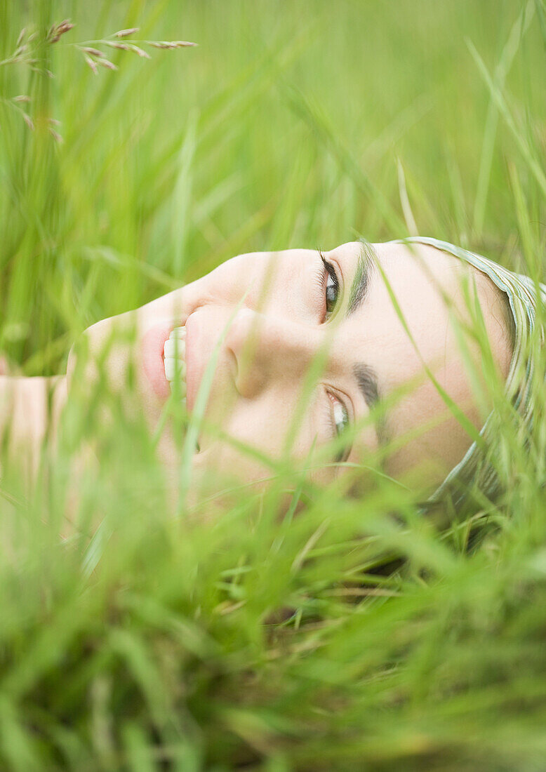 Young woman lying in grass, close-up of face