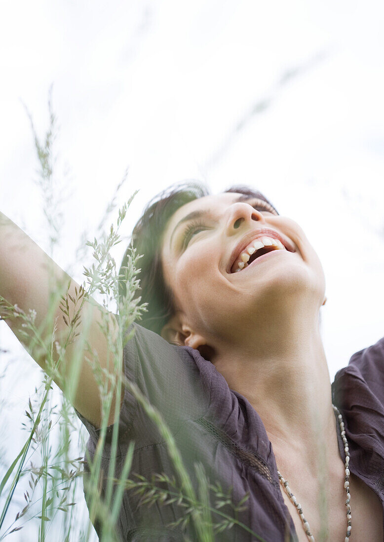 Young woman in grass, head back and smiling