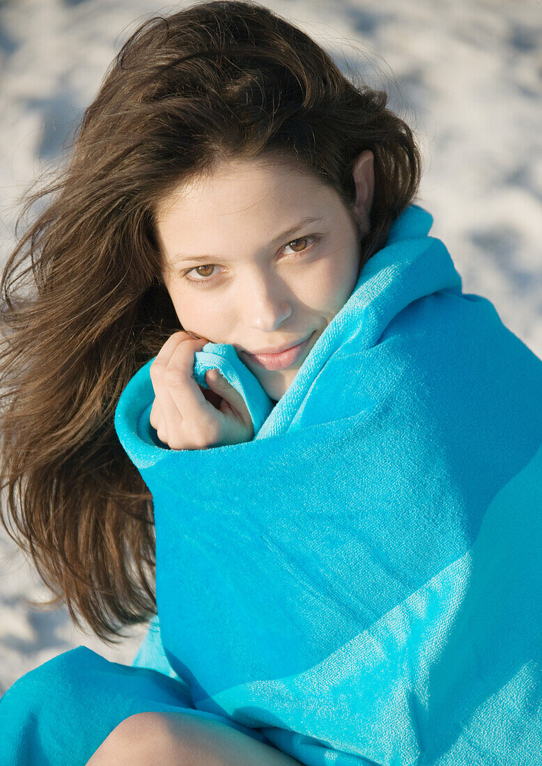 Young woman wrapped in towel at beach