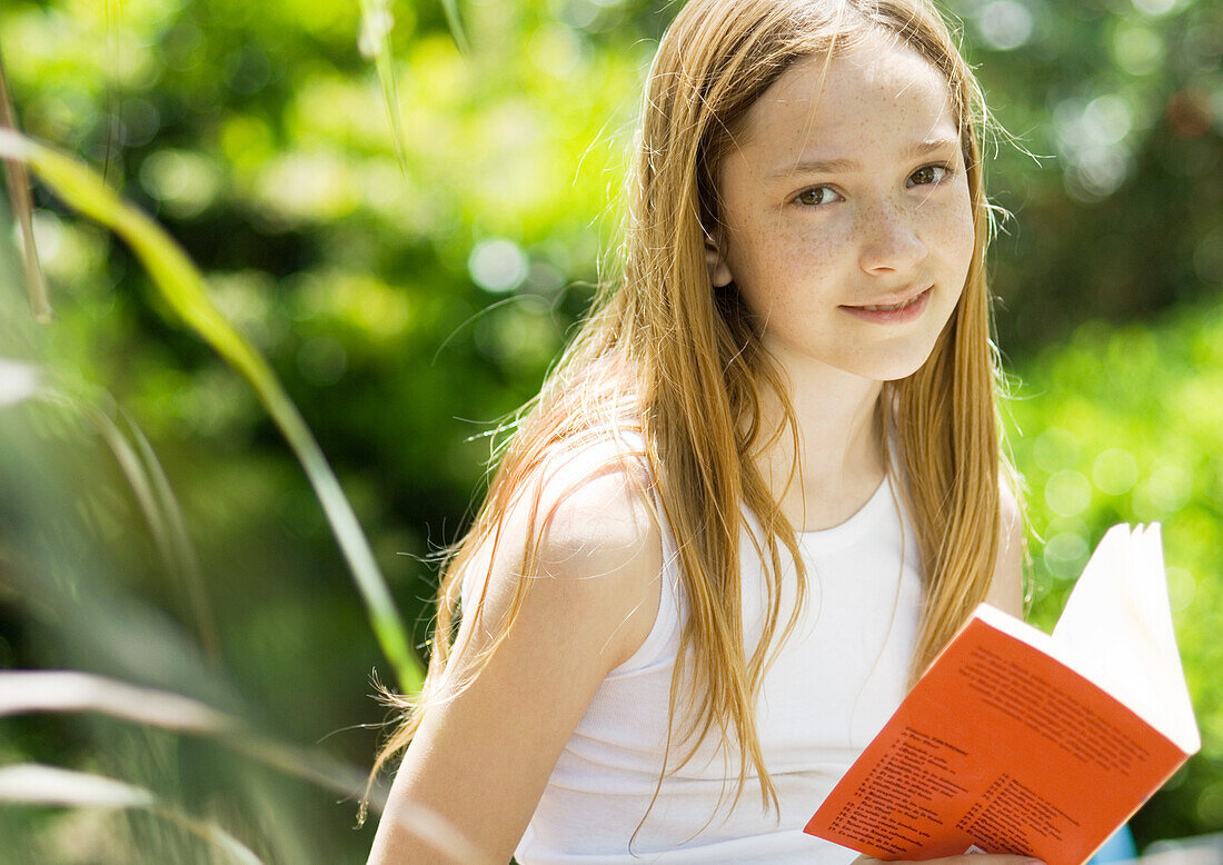 Girl with book, smiling at camera