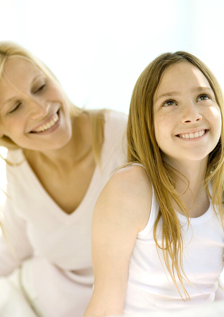 Girl smiling and looking up, mother looking over her shoulder