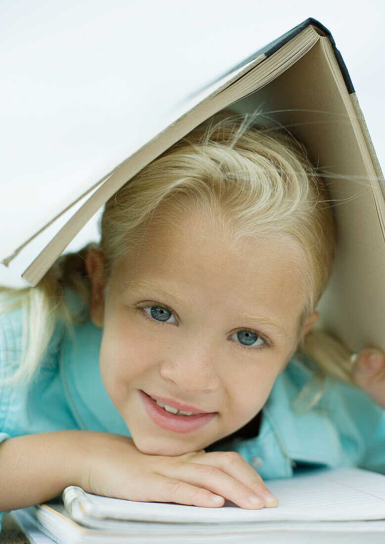 Girl holding book over head, smiling