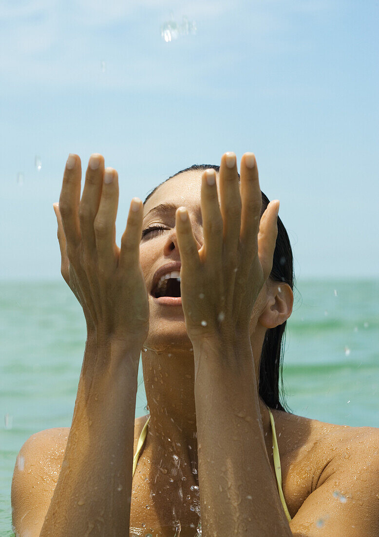 Woman in water splashing in water, eyes closed