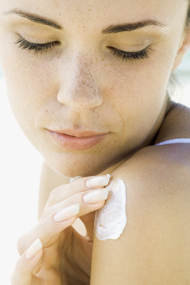 Woman applying sunscreen to shoulder, close-up