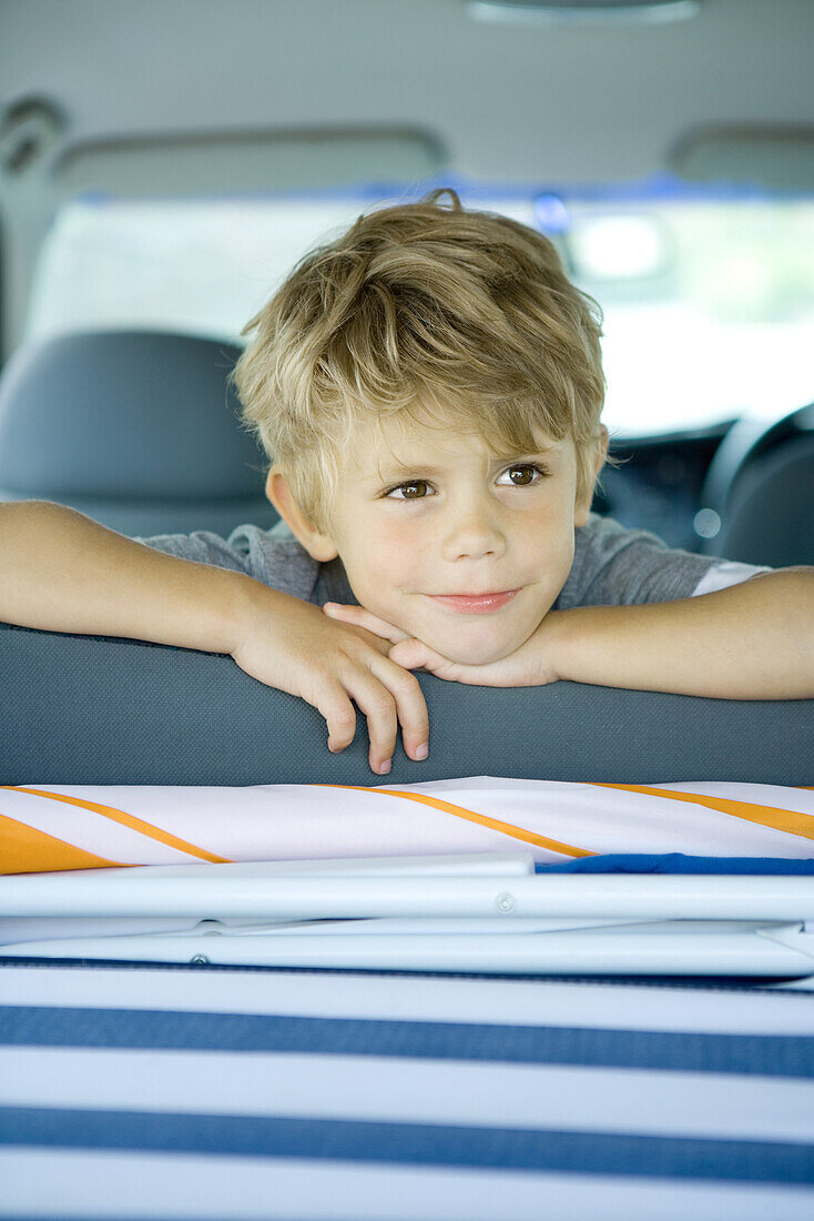 Boy in car, looking over back of seat