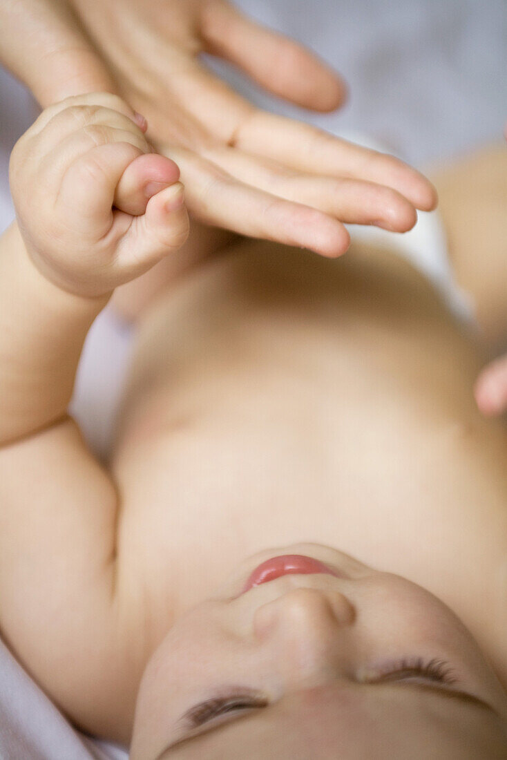 Baby lying on back, holding adult's finger