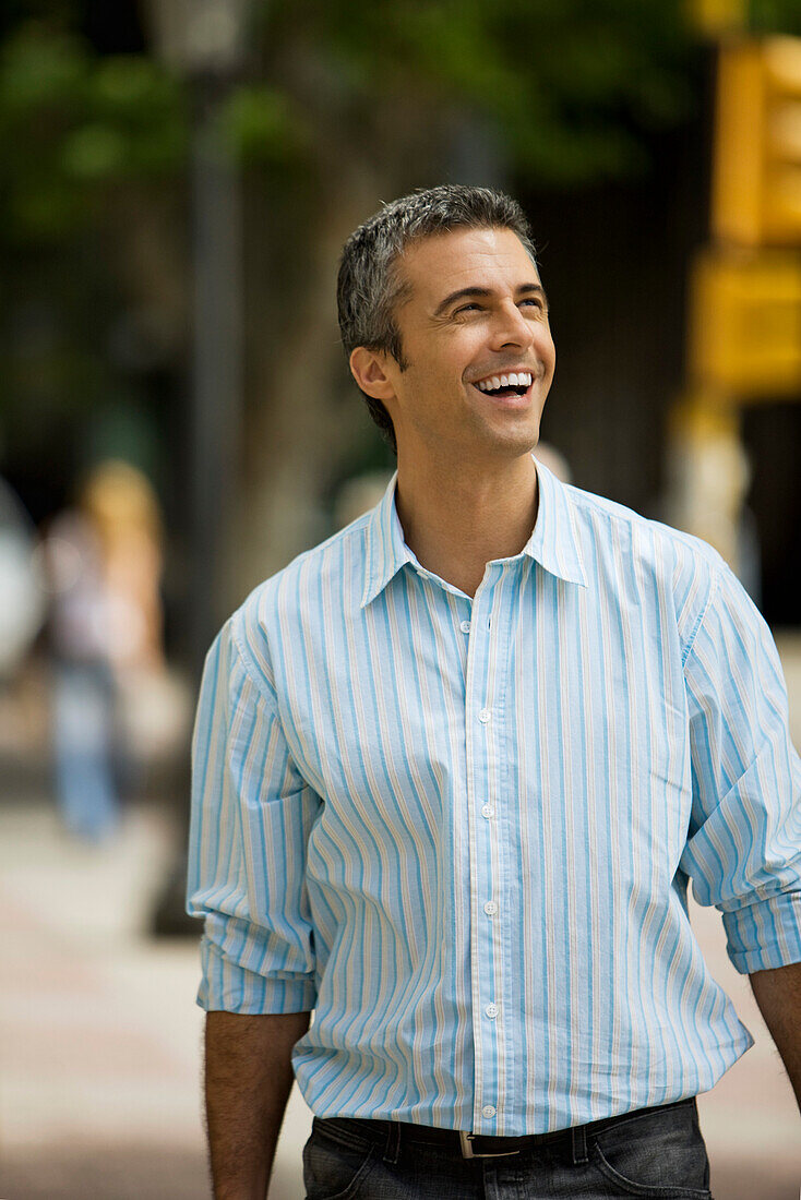 Man walking outdoors, smiling, looking away