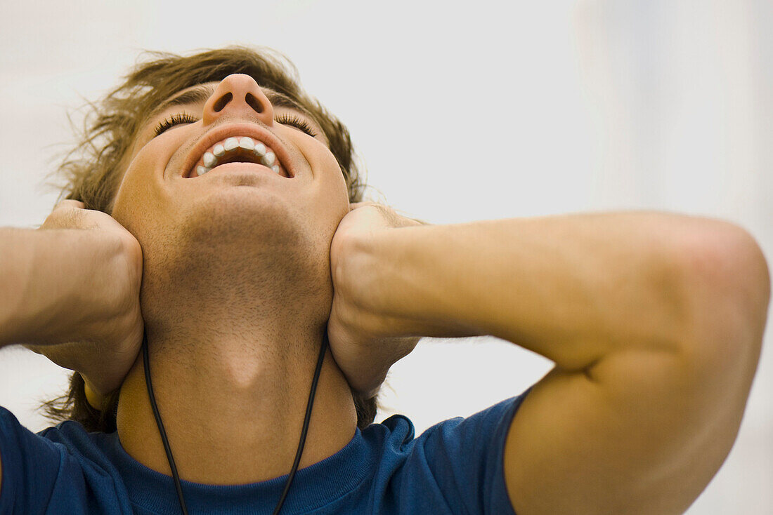 Man listening to headphones, leaning head back smiling