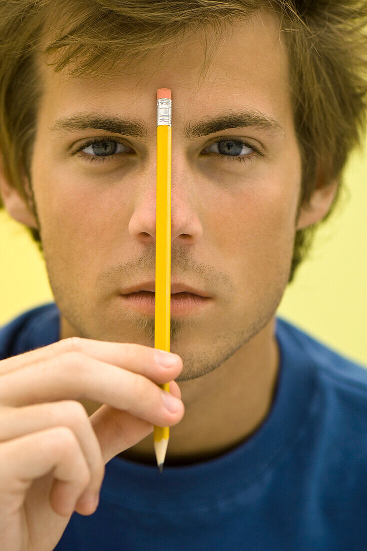 Young man holding up pencil
