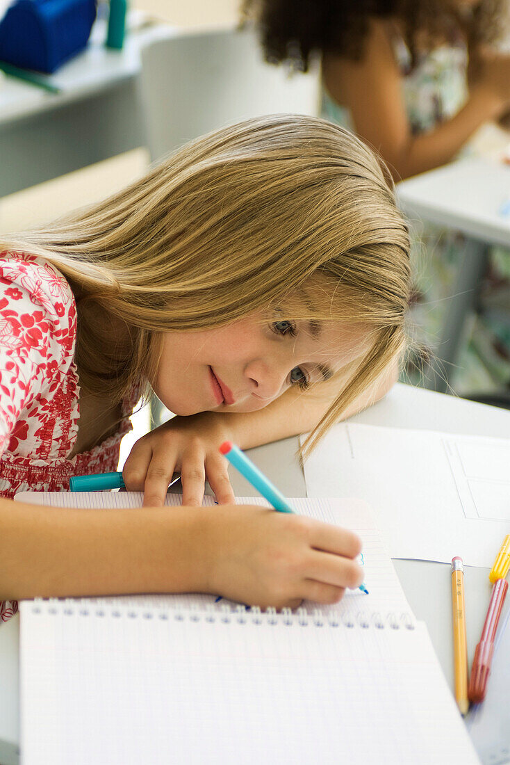 Girl resting head on arm, drawing in notebook