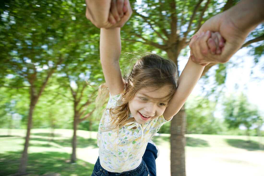 Little girl being swung through air by her arms