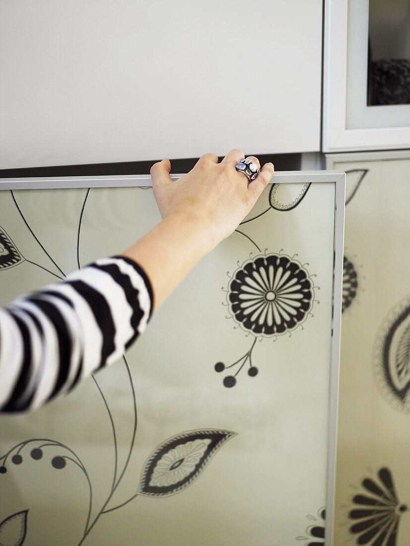 A hand opening a black and white patterned door