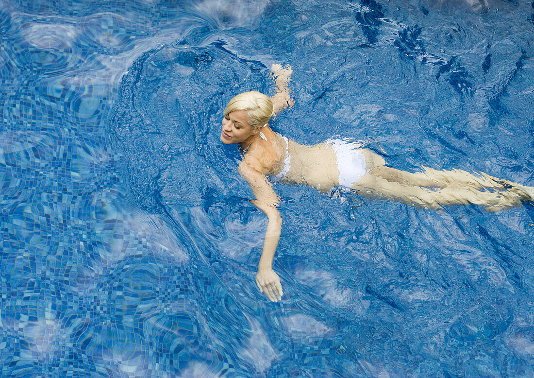 Young woman swimming in pool, high angle view