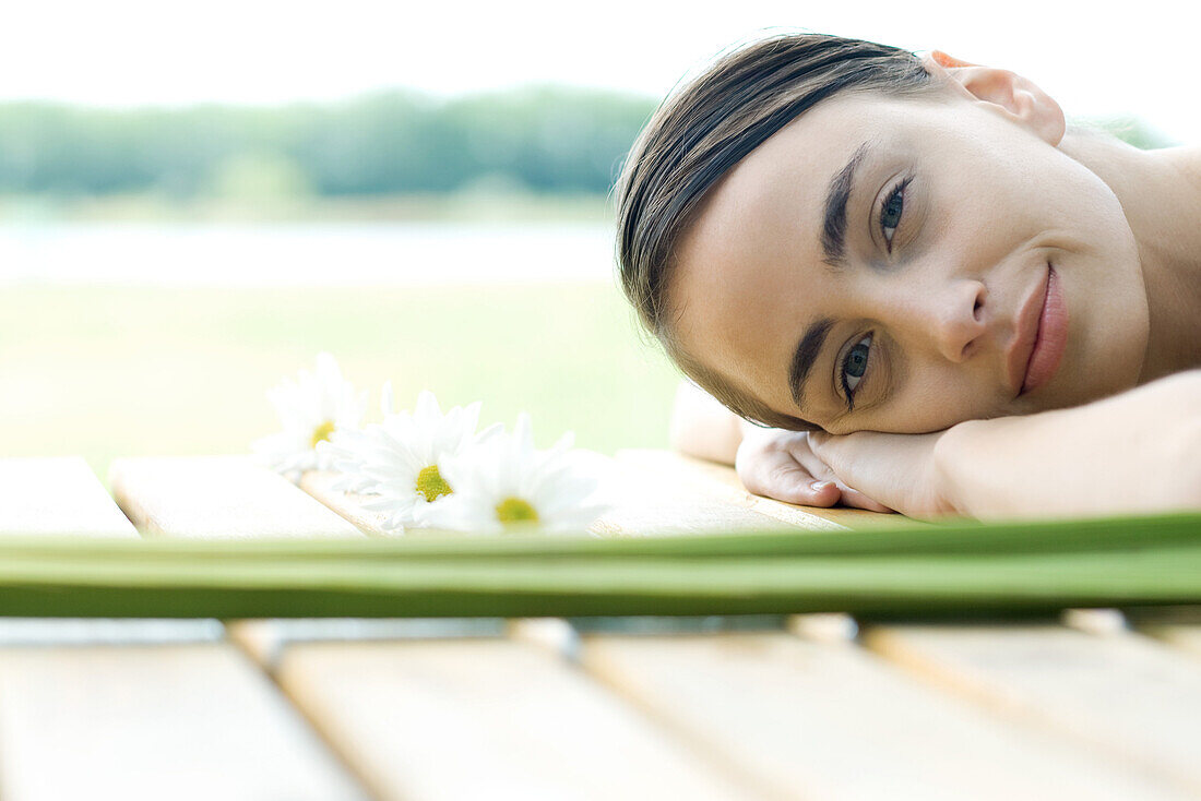 Woman lying on deck, surrounded by flowers and foliage