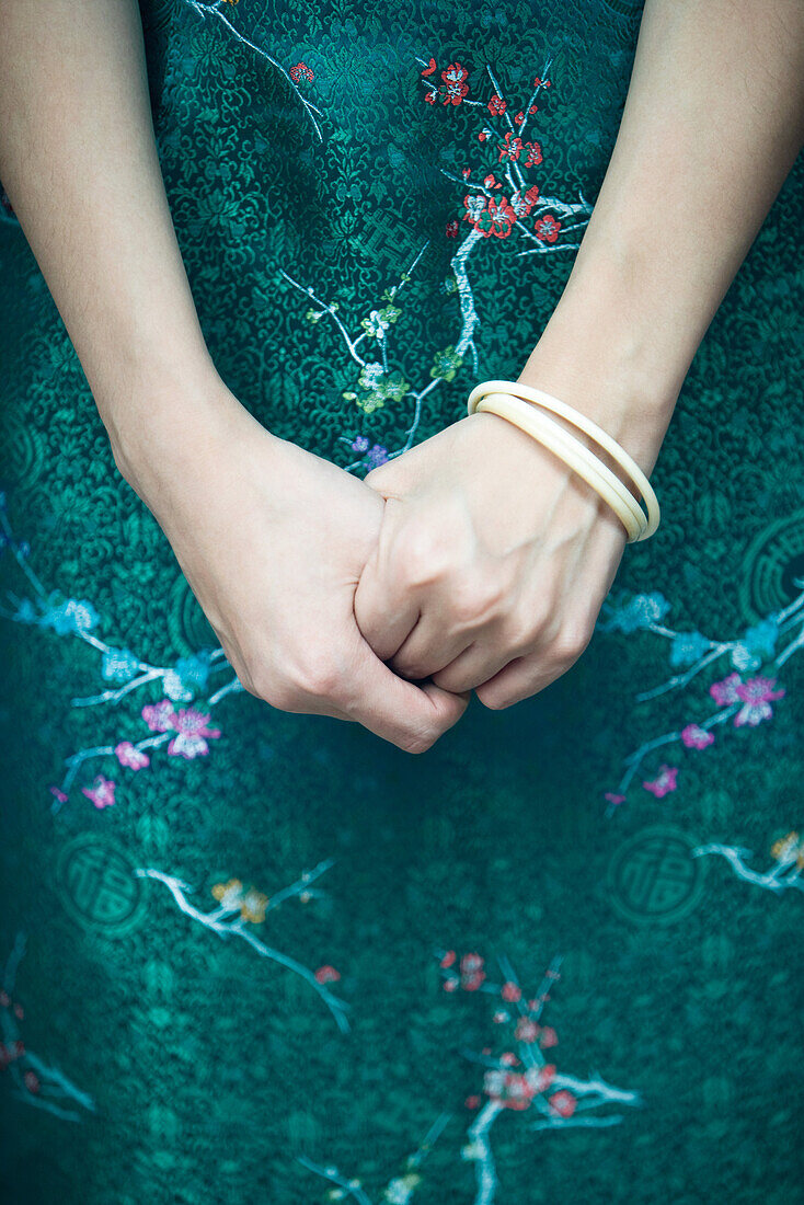 Young woman dressed in traditional Chinese clothing, hands clasped, close-up, cropped view