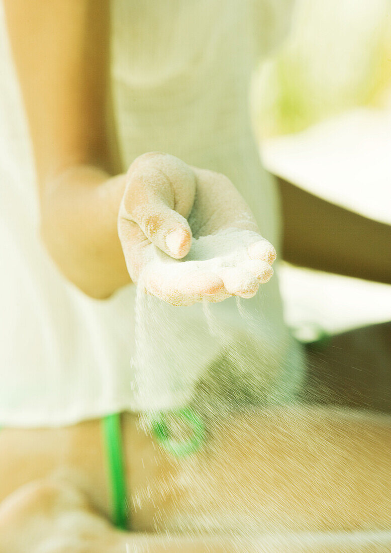 Sand blowing out of woman's hand