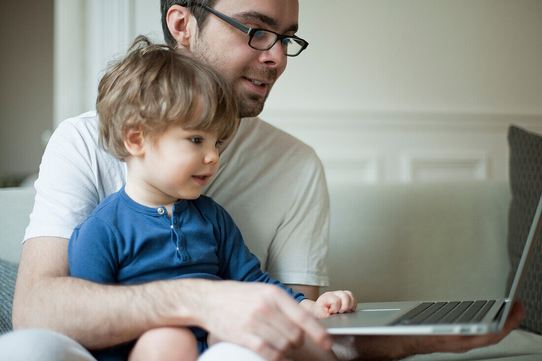 Toddler boy using laptop computer with father
