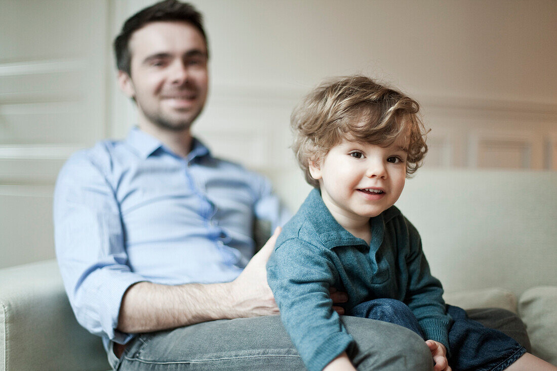 Toddler boy and father sitting on couch