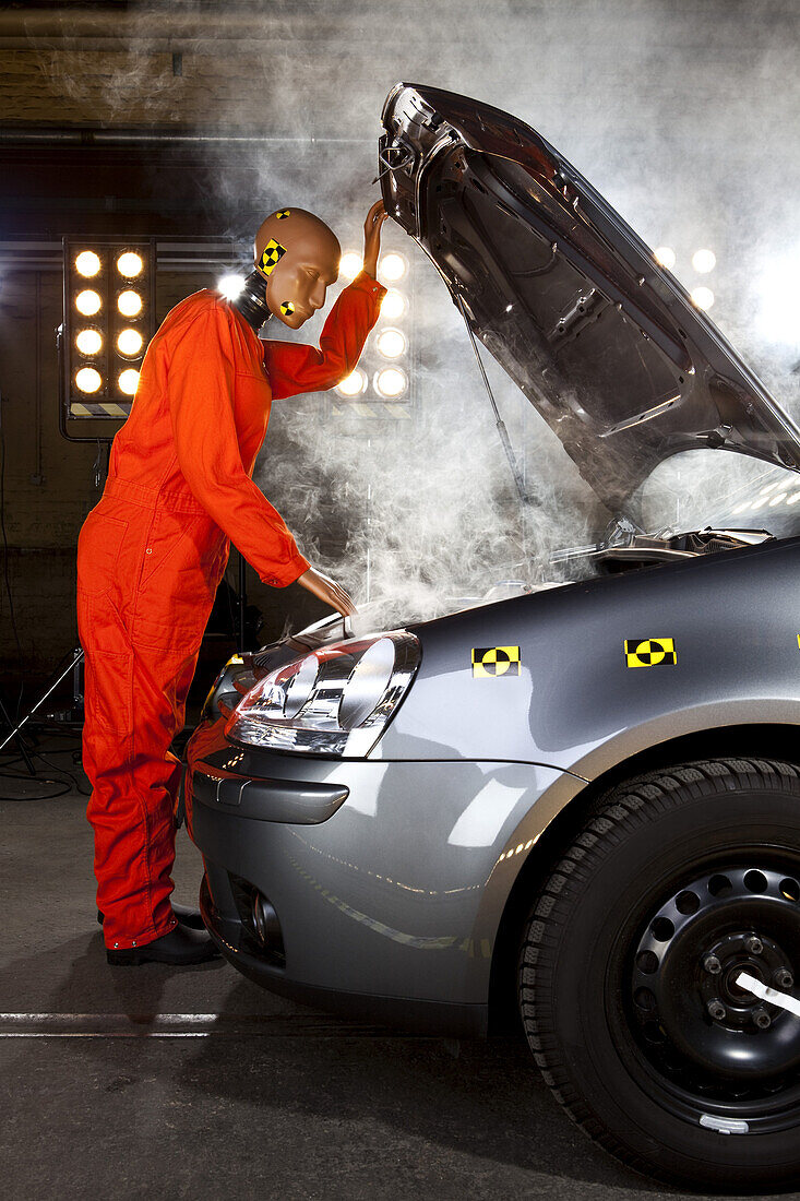 A crash test dummy checking under the hood of a smoking car