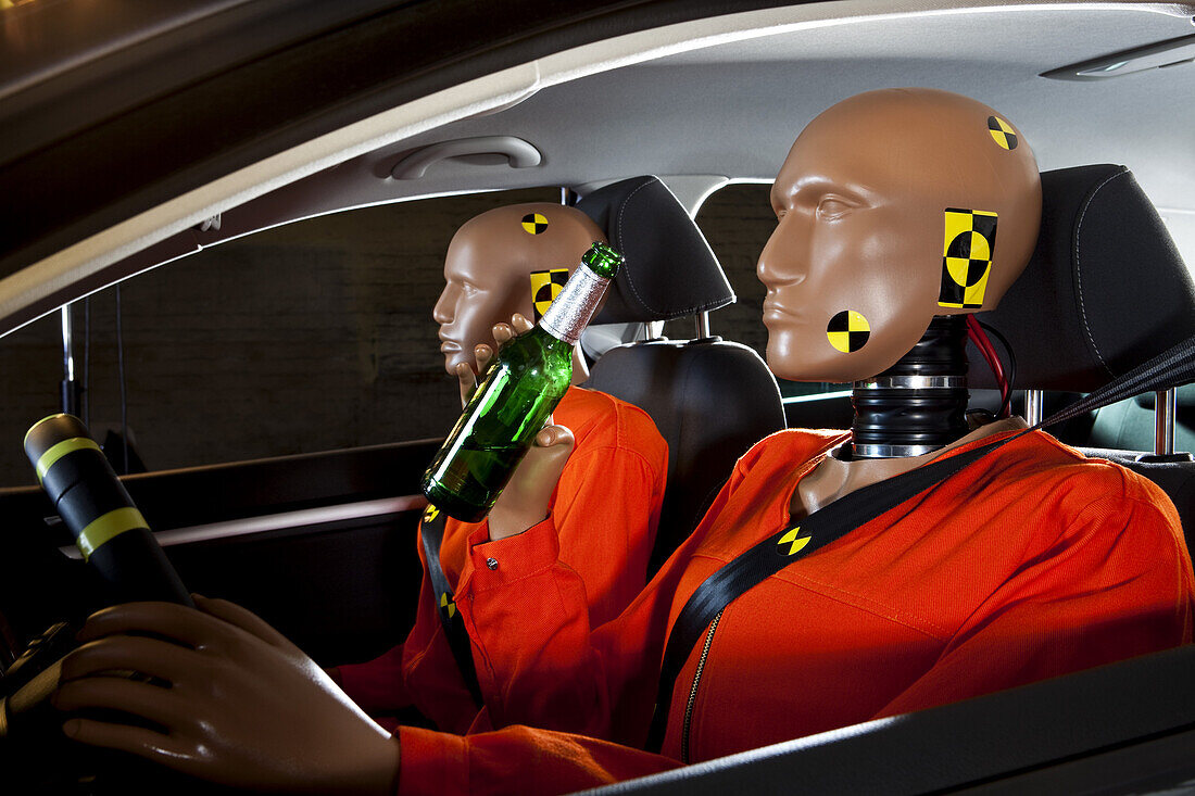 A crash test dummy drinking a beer while driving with a crash test dummy passenger