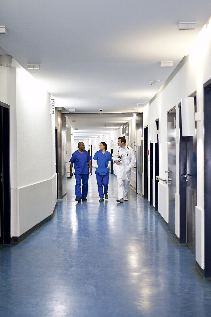 Three medical professionals walking together down a corridor in a hospital