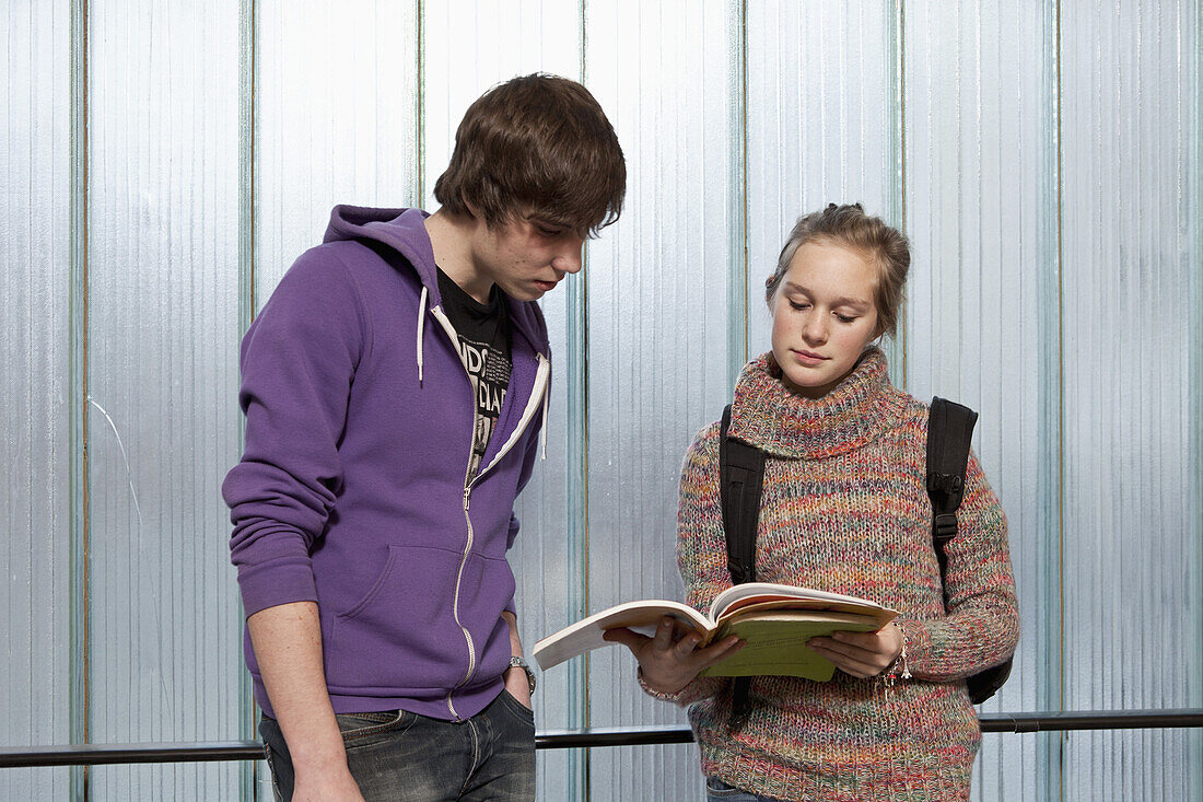 A teenage boy and girl looking at a school workbook together